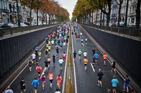 photo taken overhead of many people running a marathon on a city road