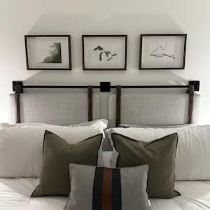 Three framed pieces above a bed's headboard